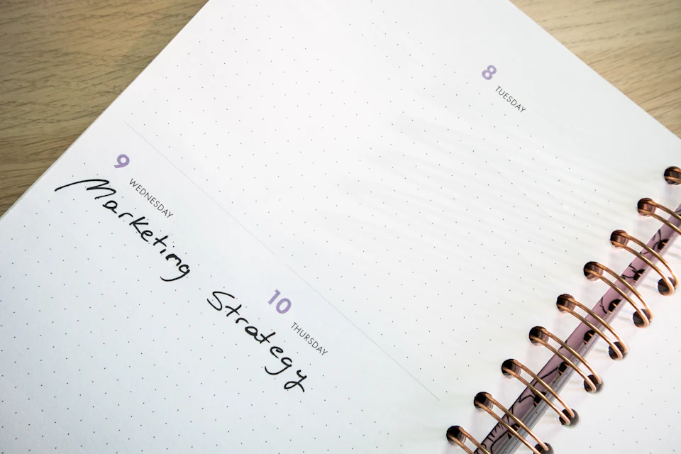 Agenda ouvert avec une note manuscrite sur la stratégie, posé sur un bureau