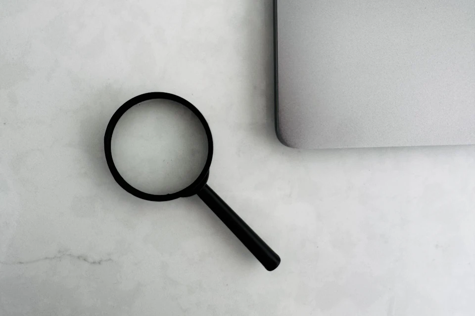 Loupe noire posée sur un plan de travail près d'un ordinateur portable