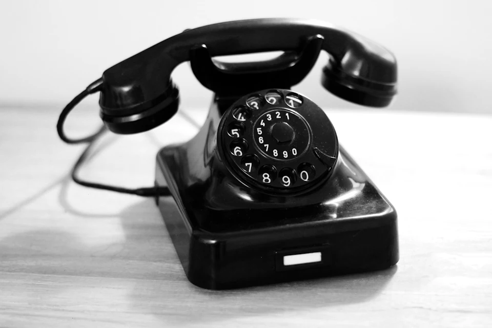 Téléphone noir à cadran posé sur une table blanche