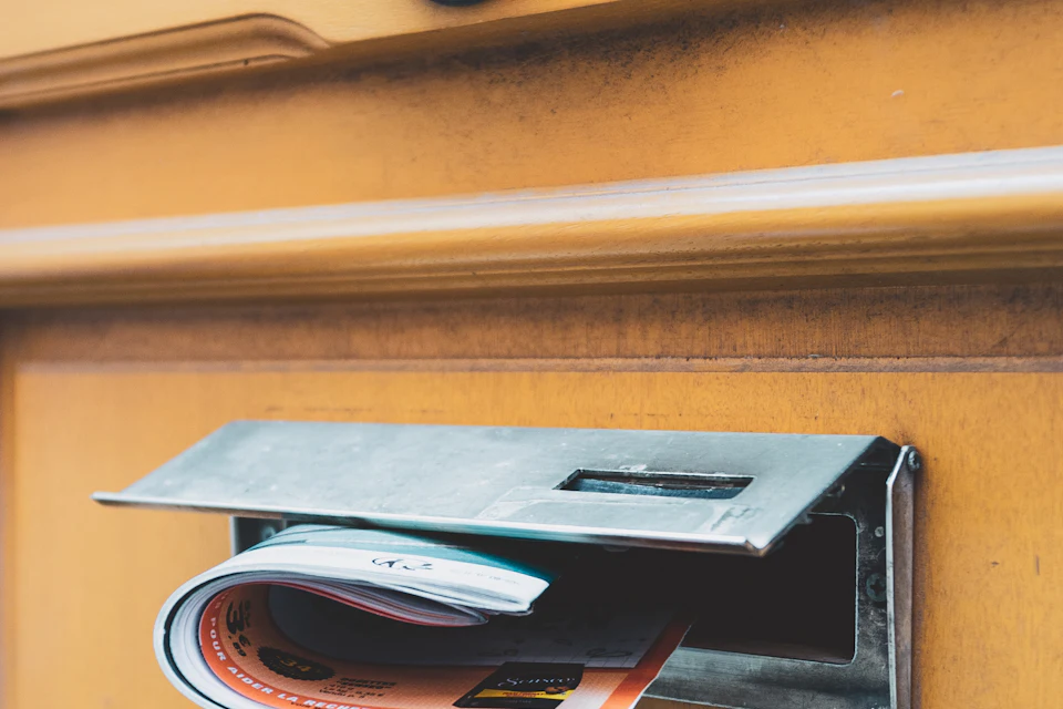 Magazine plié glissé dans la fente d'une boîte aux lettres