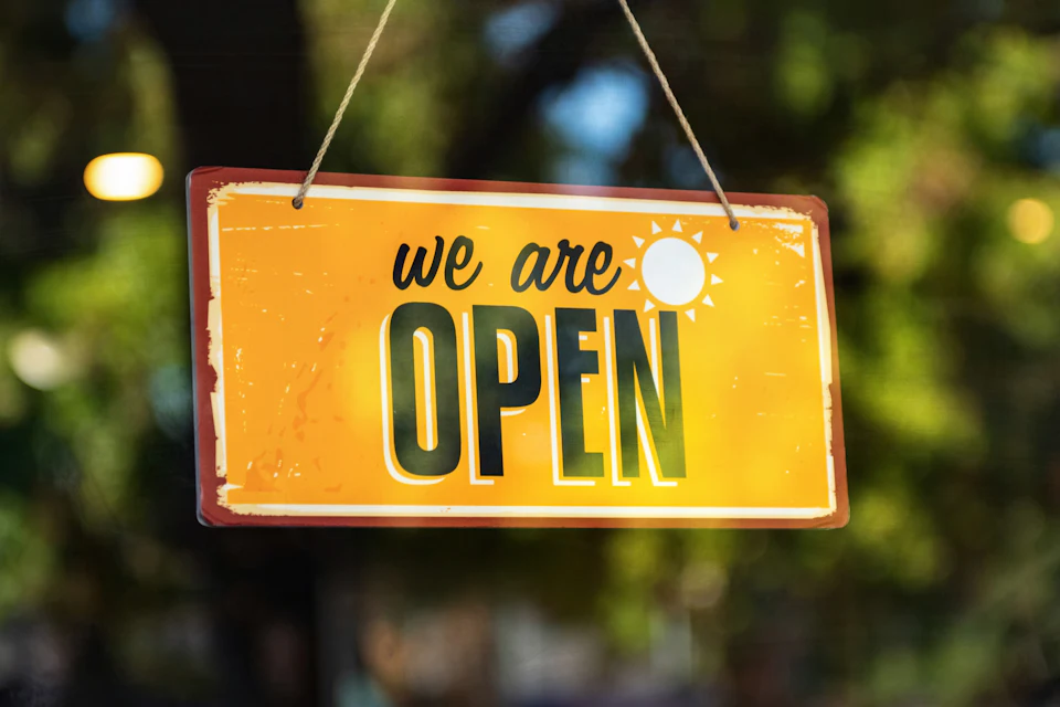 Pancarte jaune « we are open » suspendue à une porte de commerce