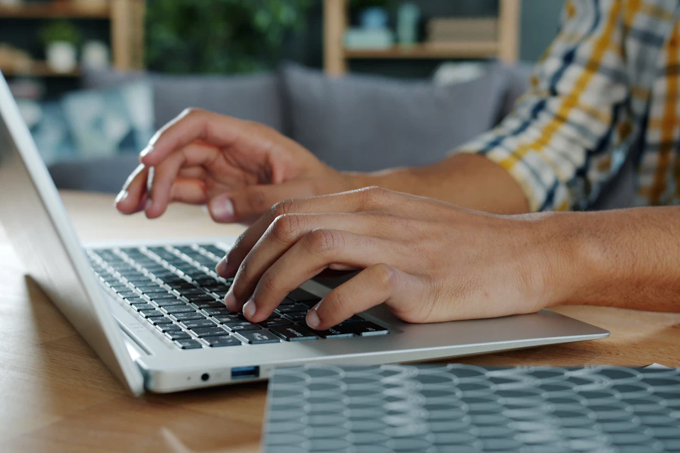 Personne tapant sur un ordinateur portable posé sur un bureau