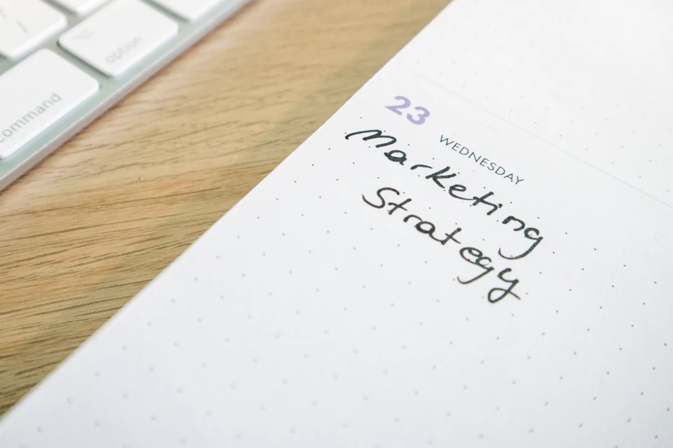 Agenda à spirale ouvert sur une page où est écrit « Marketing Strategy »
